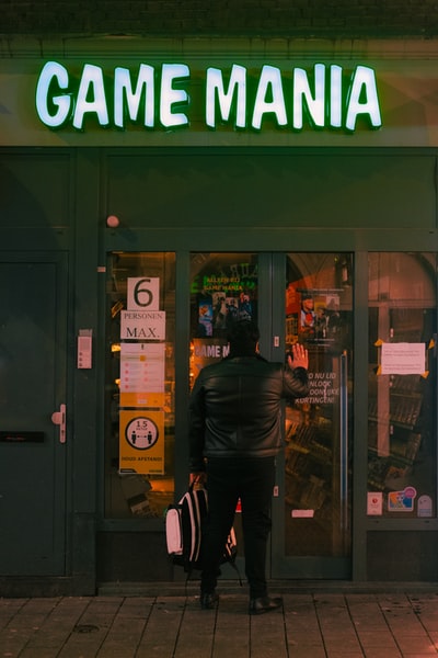 一个穿着黑色皮夹克的男人站在绿色和棕色商店附近
